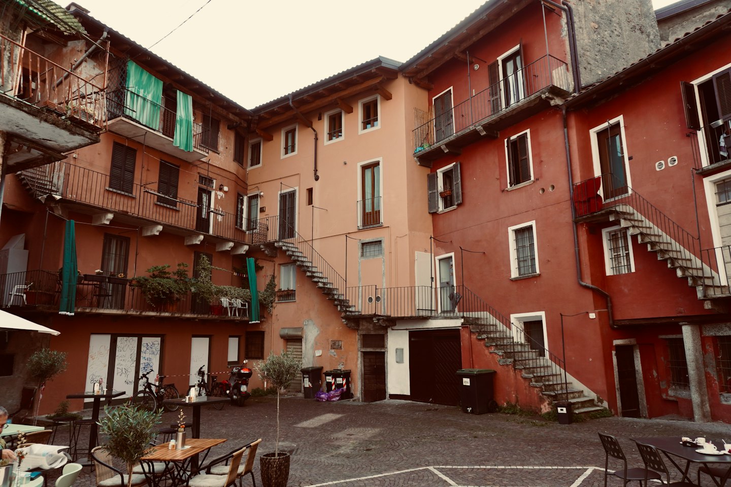 Tavoli da esterno e ulivi in un cortile storico.