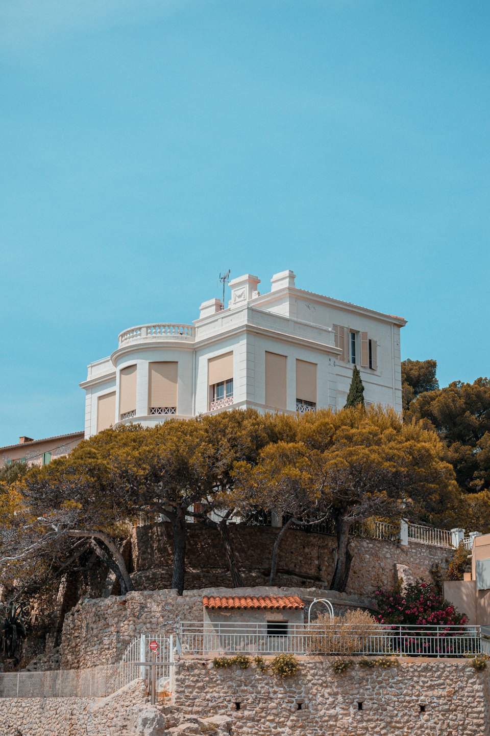Elegante villa bianca con persiane beige si erge su una collina.
