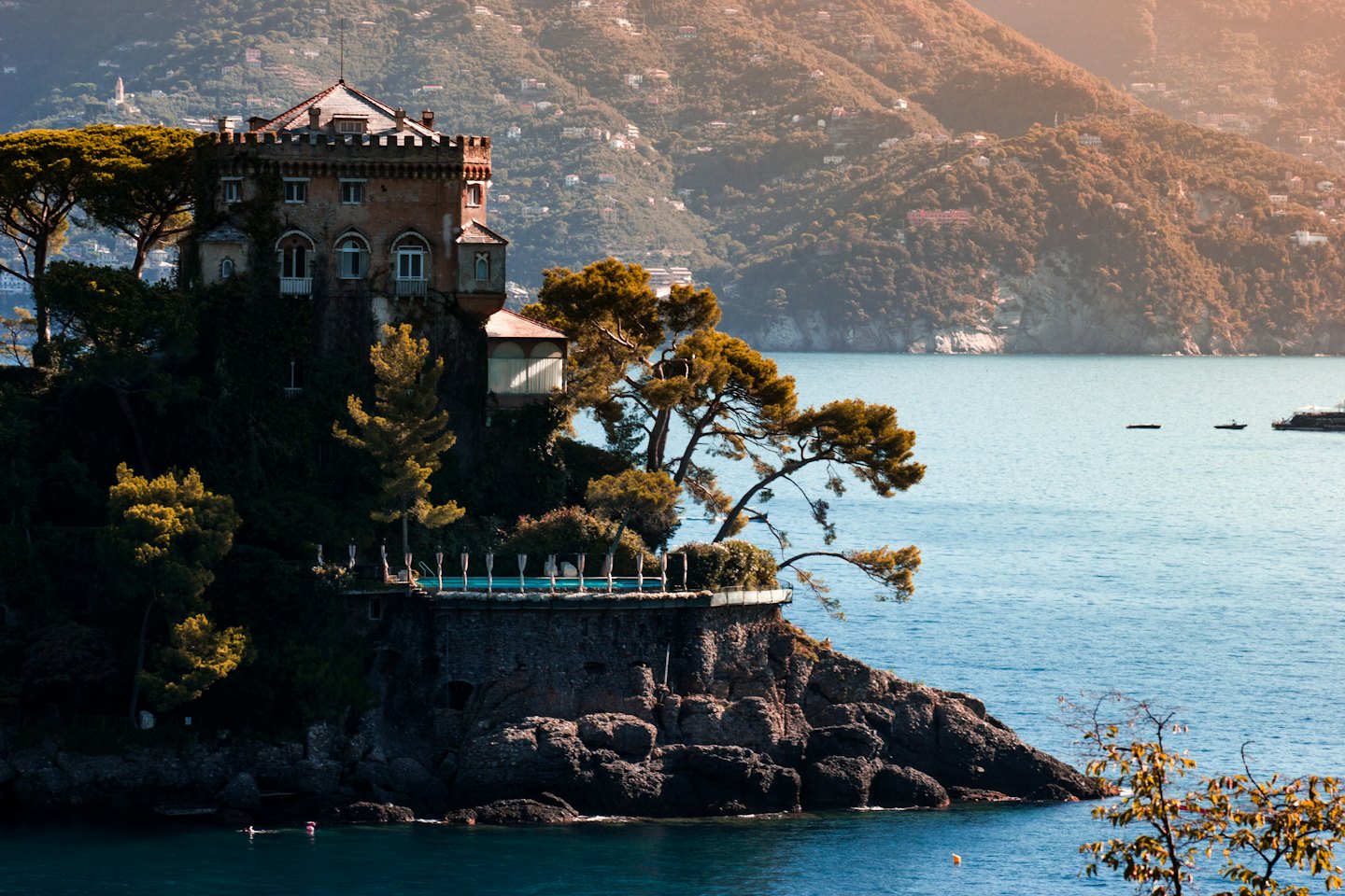 Villa su una scogliera a picco sul mare con persone che nuotano sottostanti.