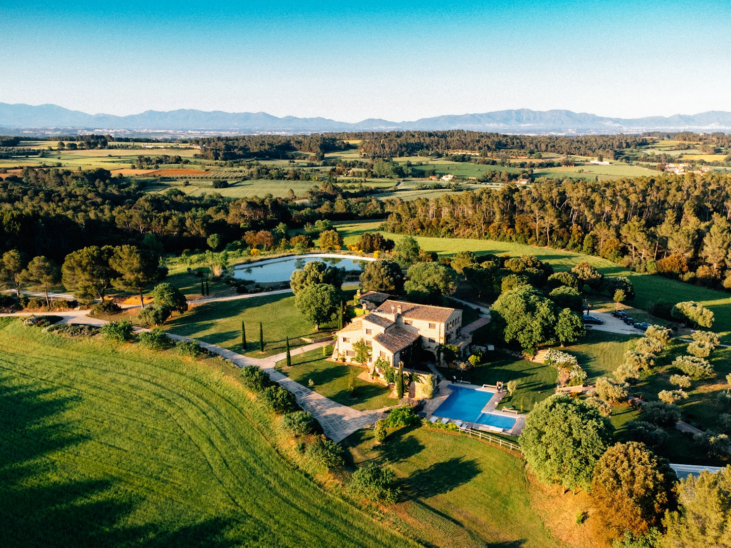 Lussuoso casale di campagna con piscina e stagno circondato dal verde.